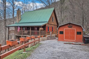 A rustic cabin with a green roof, a stone chimney, and a red door. - Welcome to Bearfeet Retreat, a pristine cabin in a quiet corner in the heart of Wears Valley. (Sevierville)