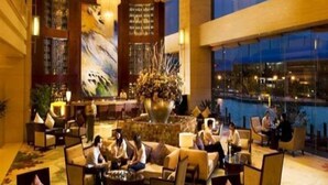 Een ruime lobby met een grote zithoek, een receptiebalie en een uitzicht op de skyline door grote ramen.