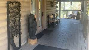 A wooden cabin with a porch, a metal tree sculpture, and a bench. - Cabin w/ loft & beautiful updates, indoor fun/hot tub/new grill & communal pool! (Sevierville)