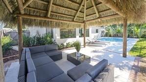 A covered outdoor seating area with a pool in the background. - Gorgeous 3B/2B Private Heated Pool mins from the beach  (Pompano Beach)