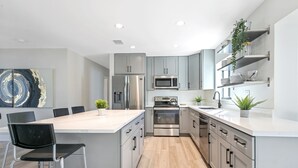 A modern kitchen with grey cabinets, stainless steel appliances, and a central island with bar stools. - Gorgeous 3B/2B Private Heated Pool mins from the beach  (Pompano Beach)