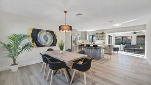 A spacious living area with a dining table, black chairs, and a modern pendant light. - Gorgeous 3B/2B Private Heated Pool mins from the beach  (Pompano Beach)