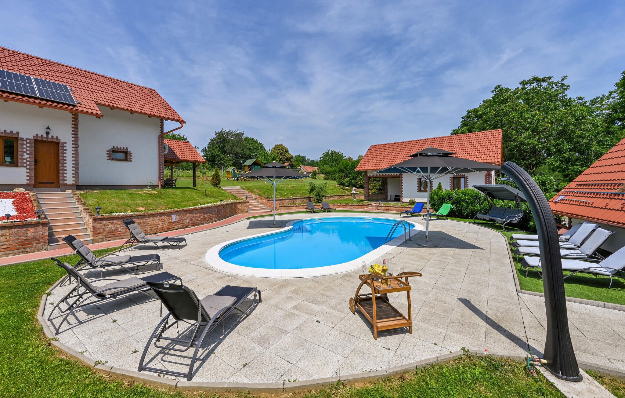 A backyard with a swimming pool, lounge chairs, and a pergola.