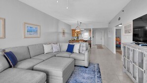 A living room with a sectional sofa, a television, and a ceiling fan. - Gulf front! 3rd floor right on the beach! With free beach service (Navarre)