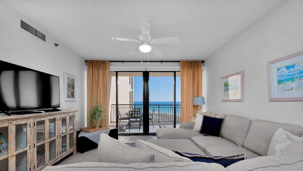 A modern living room with a flat-screen TV, a wooden cabinet, a sofa, and a balcony with a view of the sea. - Gulf front! 3rd floor right on the beach! With free beach service (Navarre)