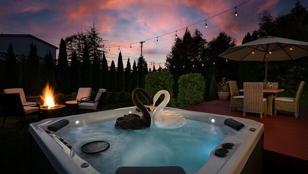A hot tub with swans, surrounded by outdoor furniture and string lights against a twilight sky. - Experience Seattle Hot Tub Firepit Backyard BBQ EV2 King Bed (Lynnwood)