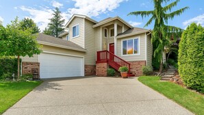 A two-story house with a red staircase, a garage, and a well-maintained lawn. - Experience Seattle Hot Tub Firepit Backyard BBQ EV2 King Bed (Lynnwood)