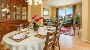 A dining area with a round table set for six, surrounded by wooden chairs. - Experience Seattle Hot Tub Firepit Backyard BBQ EV2 King Bed (Lynnwood)