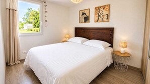Une chambre à coucher avec un grand lit, deux lampes de chevet, une tête de lit en bois et deux œuvres d’art accrochées au mur.