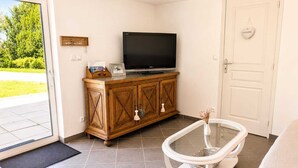 Une pièce avec un téléviseur posé sur un meuble en bois, une baignoire blanche et une porte ornée d’un motif en forme de cœur.