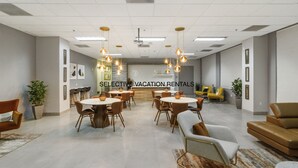 A spacious, well-lit conference room with round tables and modern chairs, featuring a neutral color palette and contemporary decor. - Miami Downtown City view 3BR Air Hockey &Ping Pong (MIAMI)