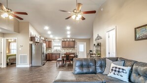 A spacious living area with a leather sofa, a dining table, and a kitchen in the background.