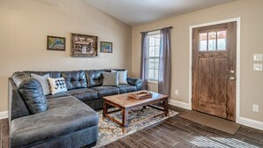 A living room with a sectional sofa, a wooden coffee table, and a patterned rug.