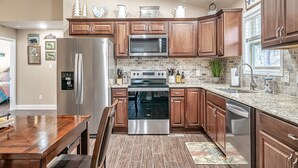 A modern kitchen with wooden cabinets, stainless steel appliances, and a brick backsplash.