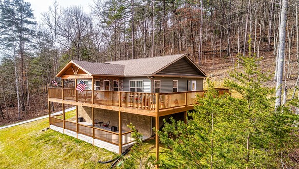 A two-story cabin with a balcony, surrounded by trees.