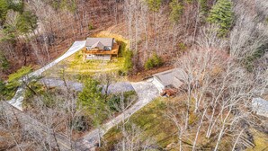 A remote cabin surrounded by dense forest, accessible by a winding road.