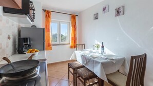 A kitchen with a stove, a coffee maker, and a bowl of fruit. There is a dining table set with plates, glasses, and a bottle of wine. - Lovely apartment in Fazana (Fazana)