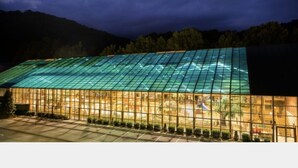 Un grand bâtiment à toit de verre offrant une vue sur un paysage montagneux.