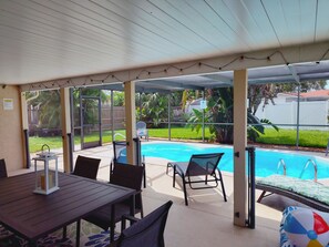 A covered outdoor area with a pool, seating, and a table. - Private HEATED Pool home in Port Richey / Essentials Provided during your stay  (Port Richey)