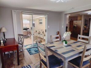 A dining area with a table set for four, a sofa, and a kitchen in the background. - Private HEATED Pool home in Port Richey / Essentials Provided during your stay  (Port Richey)