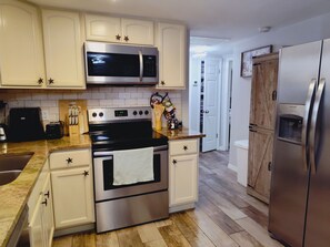 A kitchen with stainless steel appliances, white cabinetry, and a wooden floor. - Private HEATED Pool home in Port Richey / Essentials Provided during your stay  (Port Richey)