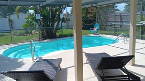 Une piscine couverte avec des chaises longues et un fauteuil doté d’un coussin.
