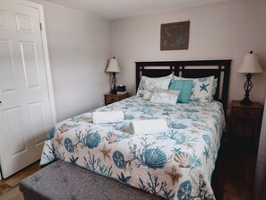A bedroom with a bed, two bedside tables, a door, and a wall decoration. - Private HEATED Pool home in Port Richey / Essentials Provided during your stay  (Port Richey)