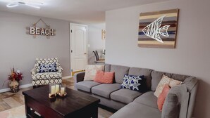 A living room with a grey sofa, patterned armchair, and a coffee table with candles. - Private HEATED Pool home in Port Richey / Essentials Provided during your stay  (Port Richey)