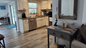 Une cuisine moderne avec des meubles blancs, un lave-vaisselle et un coin repas comprenant une table et des chaises.
