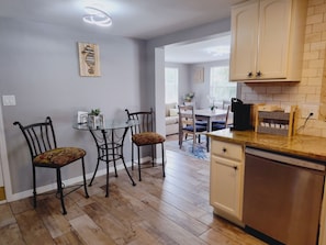 A kitchen with a dining table, chairs, and a dishwasher.