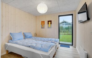 Ein Schlafzimmer mit Bett, einer Tür zu einem Außenbereich und einem Fernseher an der Wand.