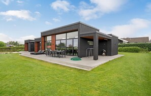 Ein modernes Gebäude mit großer Glasfassade, Außenbereich mit Sitzgelegenheiten und einer überdachten Terrasse.