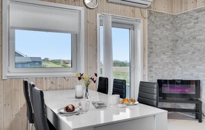 A modern dining area with a white table, black chairs, a vase with flowers, and a fireplace. - 2 bedroom lovely home in Skjern (Skjern)