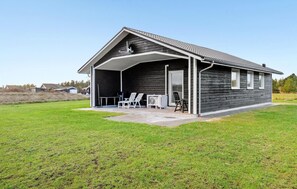 A single-story house with a covered porch, a small outdoor seating area with chairs, and a grassy yard. - 2 bedroom lovely home in Skjern (Skjern)
