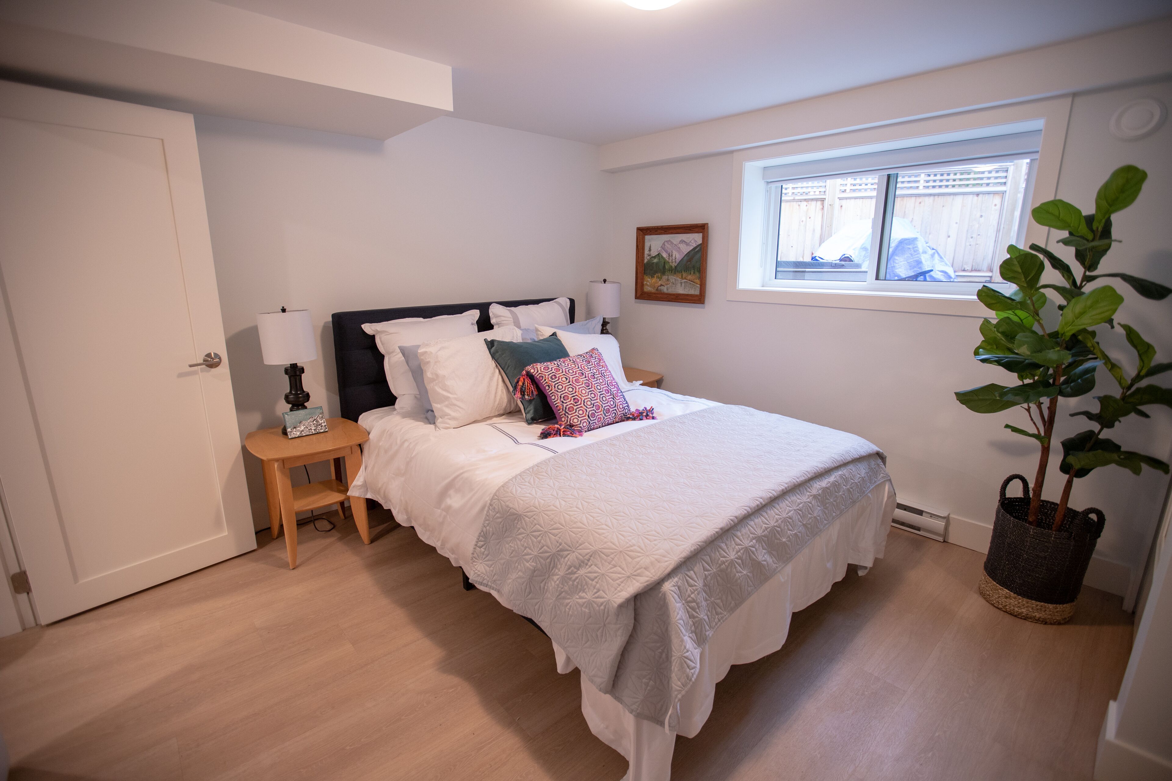 Une chambre à coucher avec un lit, une table de chevet, une lampe et une plante en pot.