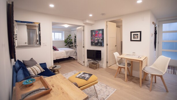 Ein modernes Wohnzimmer mit einer Couch, einem Couchtisch und einem Essbereich mit Stühlen. Ein Fernseher und ein Kamin sind ebenfalls vorhanden.