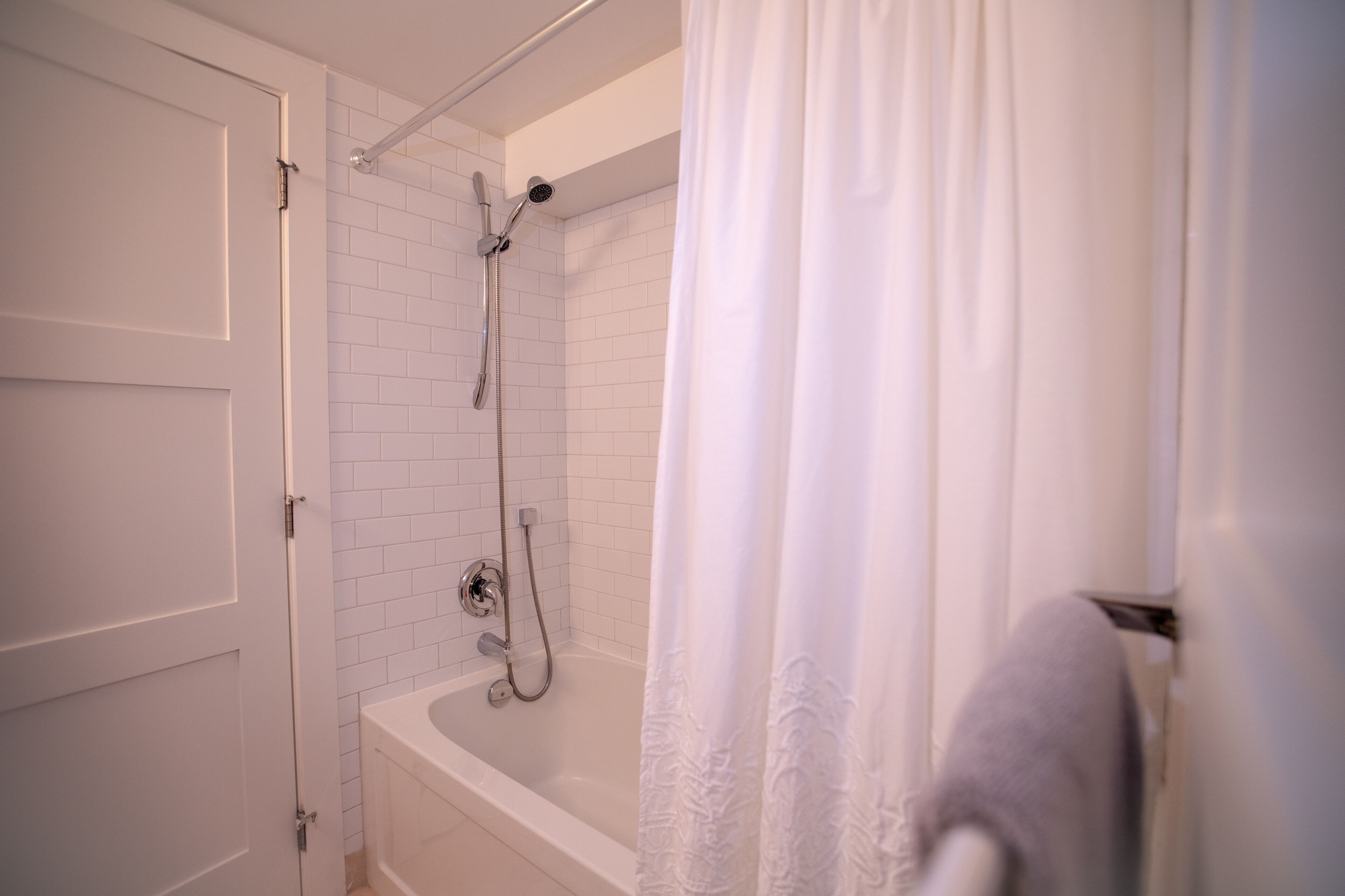 Un baño con una bañera blanca, un cabezal de ducha y un perchero para toallas.