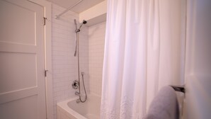 Ein Badezimmer mit einer weißen Badewanne, einer Duschbrause und einem Handtuchhalter.