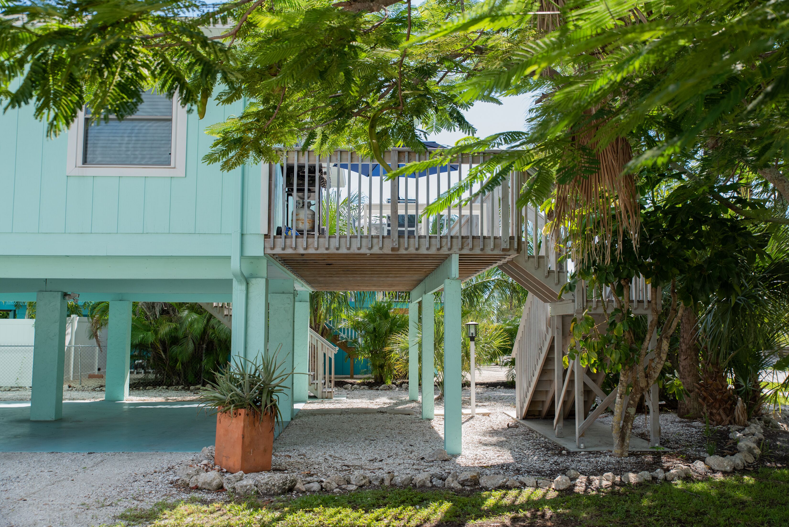 A light blue house with a wooden deck and a covered patio area.