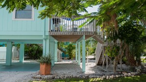 A light blue house with a wooden deck and a covered patio area.