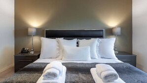 Ein ordentlich bezogenes Bett mit weißen Bettwäsche, zwei Nachttischlampen und einem Telefon auf dem Nachttisch.