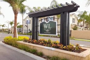A sign for West Lucaya Village Resort with a pergola structure and landscaped garden.