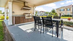 Eine Terrassengruppe mit Grill, Sitzgelegenheiten und Blick auf Wohnhäuser.