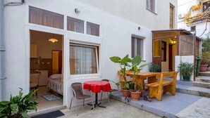 A small, cozy outdoor seating area with a table and chairs, surrounded by potted plants.