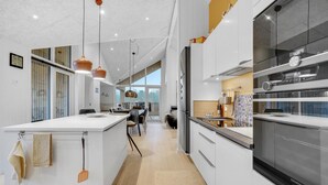 A modern kitchen with a central island, stainless steel appliances, and pendant lighting. - 4 bedroom stunning home in Sjølund (Sjølund)