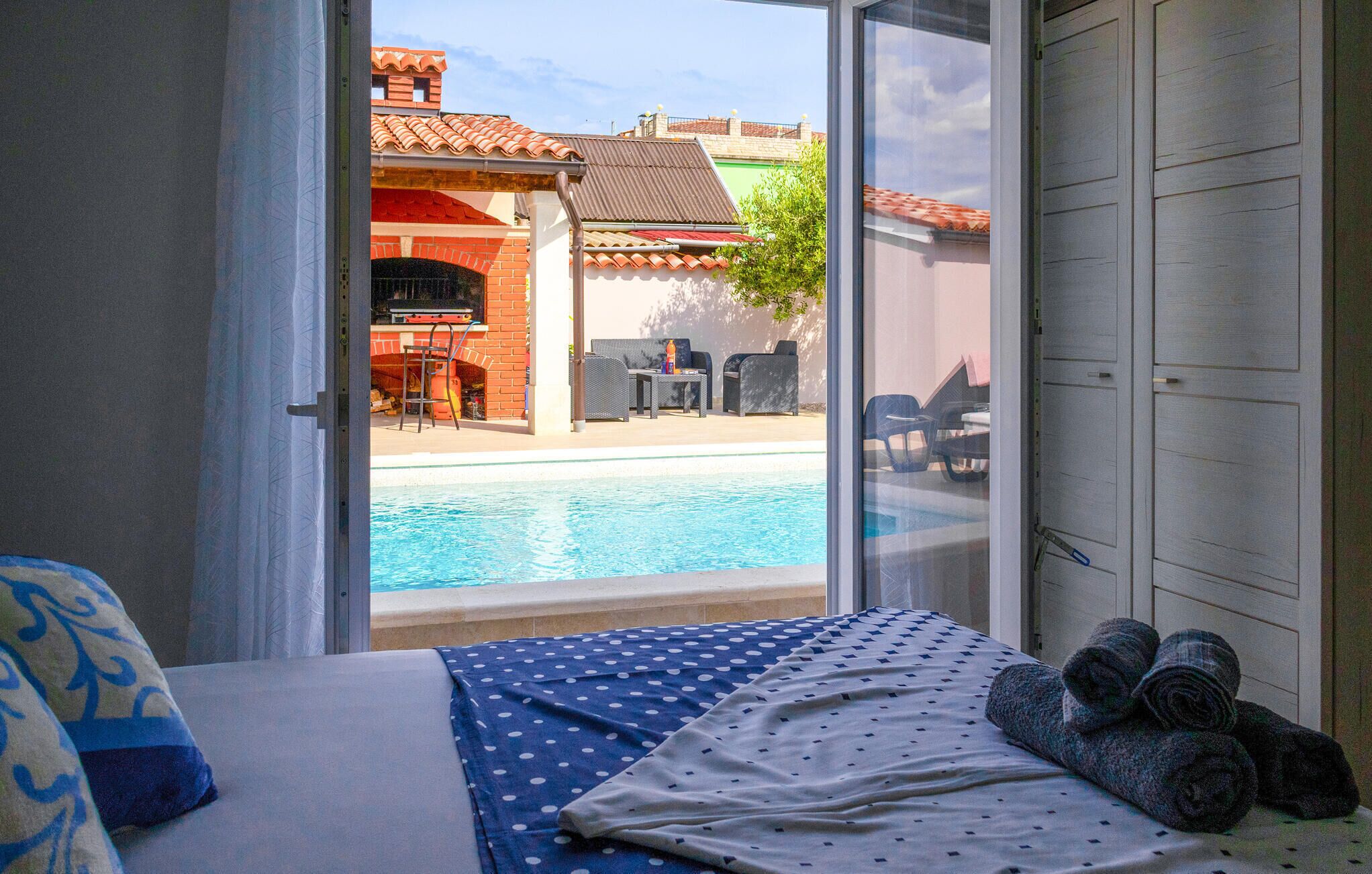 Habitación de hotel con cama, vista a una piscina y zona de barbacoa.