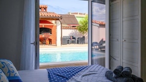 A hotel room with a bed, a view of a swimming pool, and a barbecue area. - Stunning home in Galizana (Galizana)