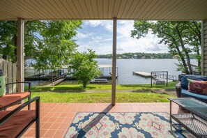 Relax on the patio with a serene view of the lake, surrounded by lush greenery and a comfortable seating area.
