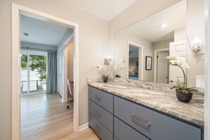 Bathroom features a large mirror and a countertop, with two potted plants and a light fixture.