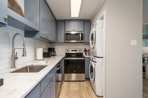 Enjoy cooking in this well-equipped kitchen with a stainless steel sink, microwave, compact oven, and washing machine.
